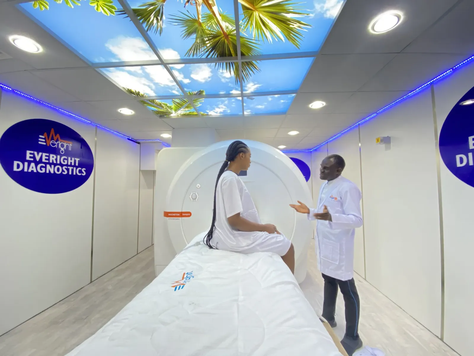 A patient seated on the scanner bed of Everight's 1.5 Tesla Siemens MAGNETOM MRI while a radiographer explains the examination